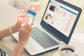 Woman using Facebook on a cell phone and laptop