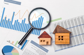 Wooden houses and magnifying glass on spreadsheets