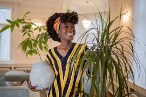 Young woman in a striped shirt holding plants in a home