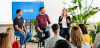 Three business employees sitting on stools and giving a seminar to a group of people.