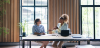 Two business women sitting at the table, having a meeting at the office. They are discussing proj