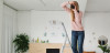 A woman photographer aims her camera toward the viewer while standing on a step stool.