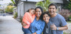 Multi-ethnic parents and children are smiling on driveway. 