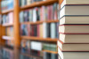 Many books stacked with blurred background of bookstore full of books