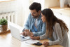 Couple looking at laptop screen analyzing expenses managing family budget