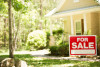 Home for sale with real estate sign in spring or summer season.