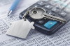 Financial papers, calculator, key on house keychain