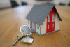 home keys on a table next to a toy house