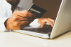 Man holding a credit card and typing on a laptop