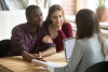 African american husband telling real estate agent description of residence he wants, his wife smiling and listening.