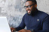 Man with R badge smiling at laptop