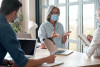 Older woman mentoring two younger people in an office