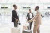 Three people with suitcases talking to each other in an airport