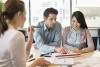 Young couple and businesswoman reviewing papers