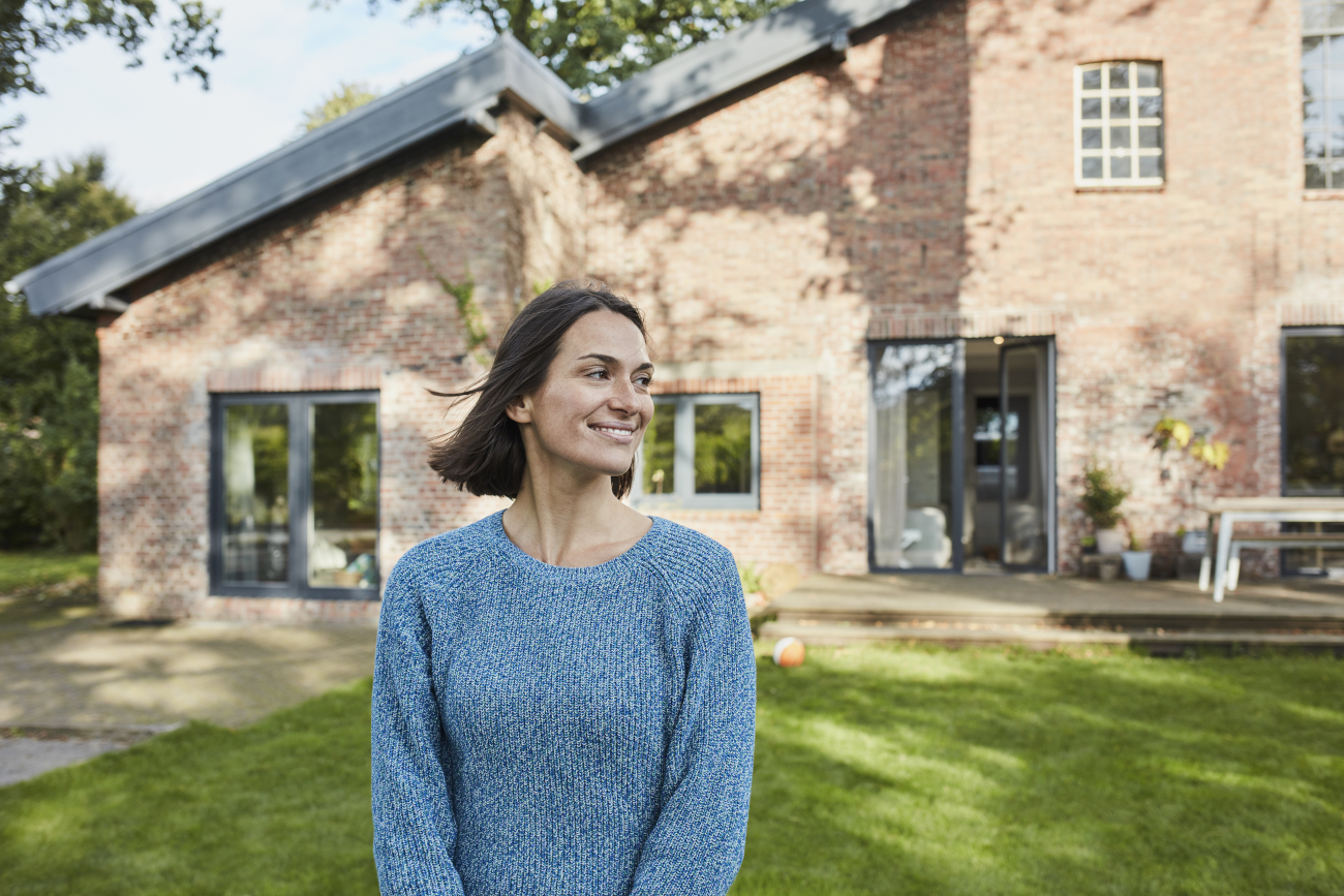 A woman standing in front of a house, smiling.  